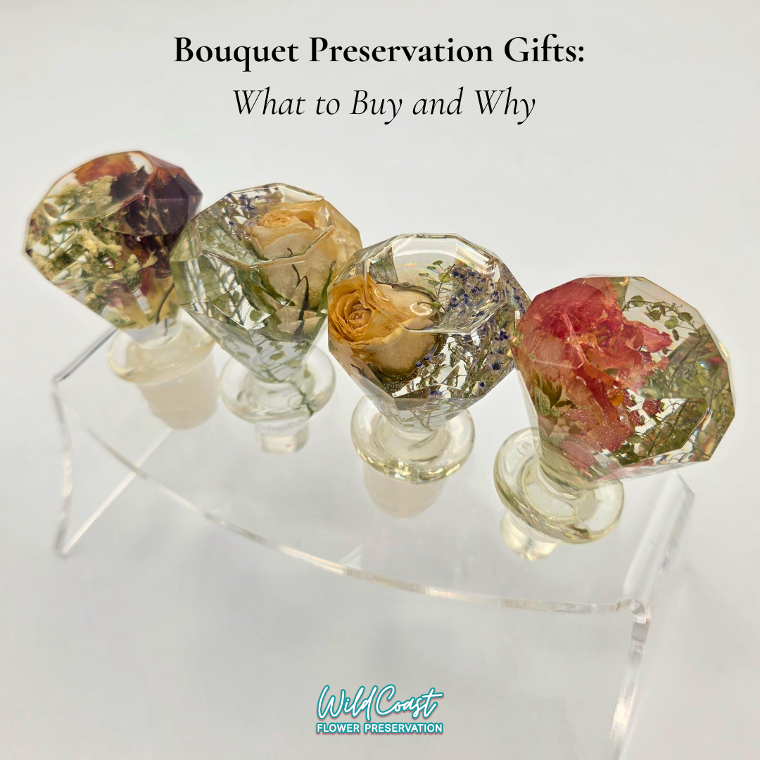 Four clear resin preserved flower wine stoppers on a clear display rack on a white background with blog title Bouquet Preservation Gifts