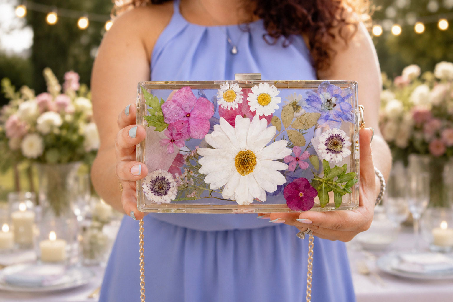 Person holding a preserved flower resin clutch purse with a blurred outdoor setting