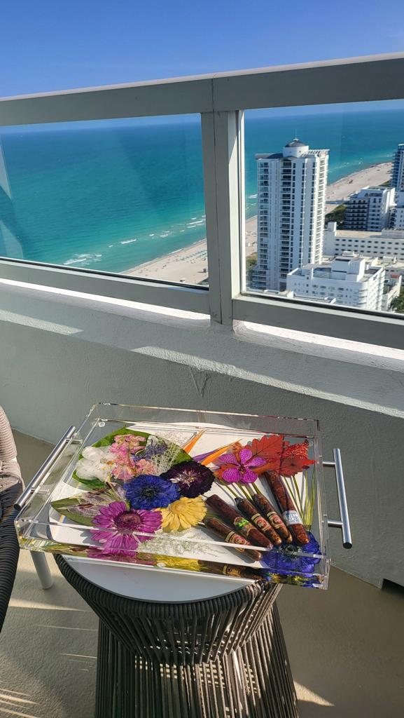 Balcony view from Fontainebleau South Beach with serving tray showcasing pressed tropical flowers and cigars preserved in epoxy with silver side handles