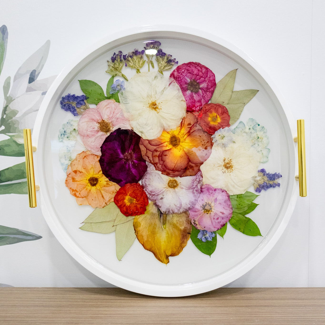 resin pressed flower round white ottoman tray with mixed pressed flowers inside clear epoxy on a countertop