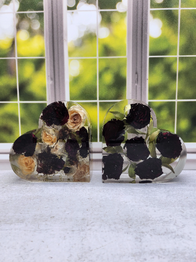 A heart-shaped resin bouquet block with preserved red roses arranged inside with a clear resin finish, displayed on a flat surface.