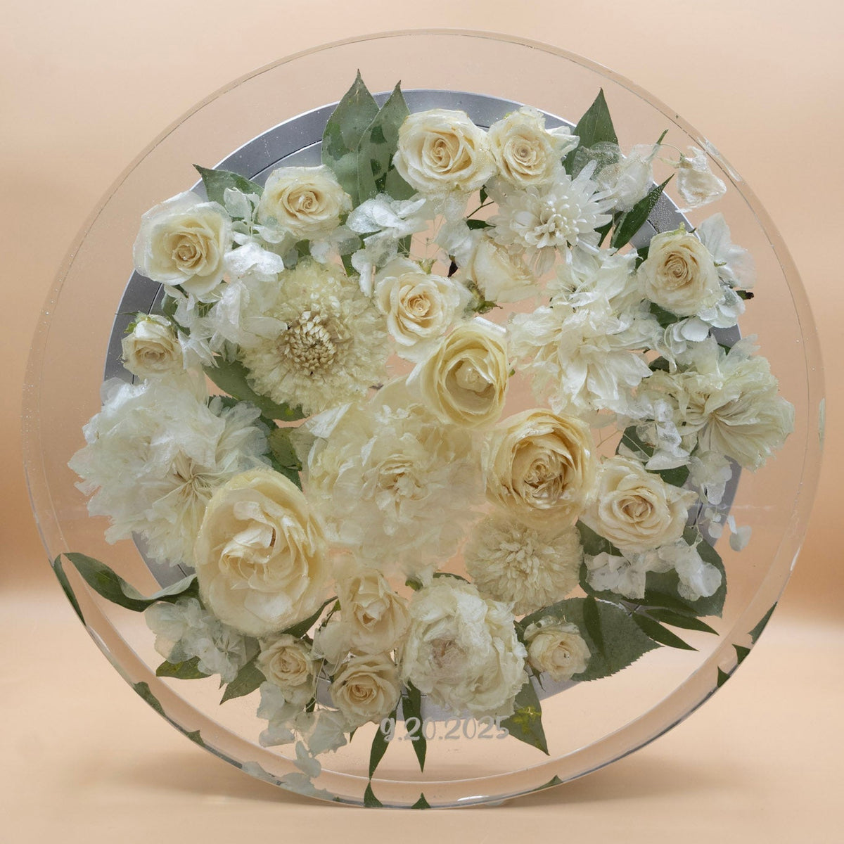Standing view of A preserved flower lazy susan whole white peony and white dahlia dried flowers and green leaves, encased in resin lazy susan with rotating base set against a solid beige background.