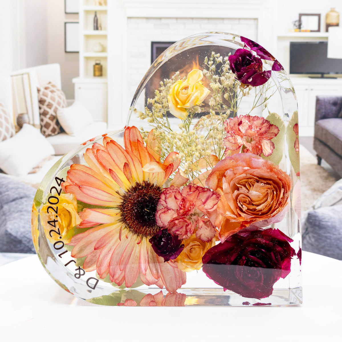 A heart-shaped block of preserved fall wedding bouquet flowers displayed in a room, featuring a mix of floral colors with a visible wedding date text customization on the bottom.