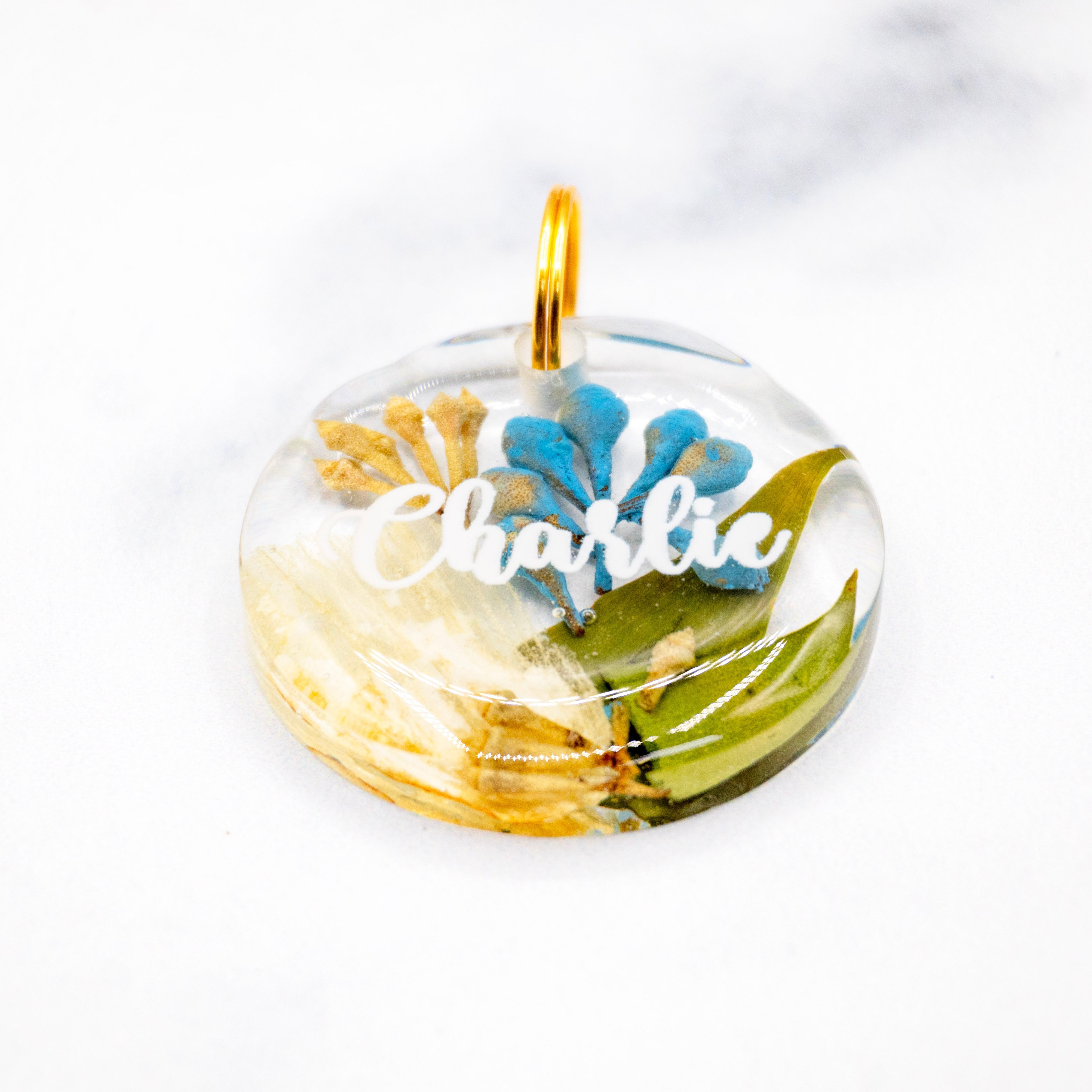 Landscape photo of a pressed flower resin pet tag set with mixed dried botanical layers