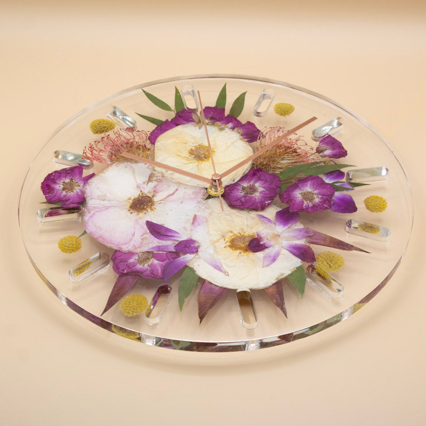 Flower preservation wall clock with pressed flowers of a tropical wedding bouquet on a beige background