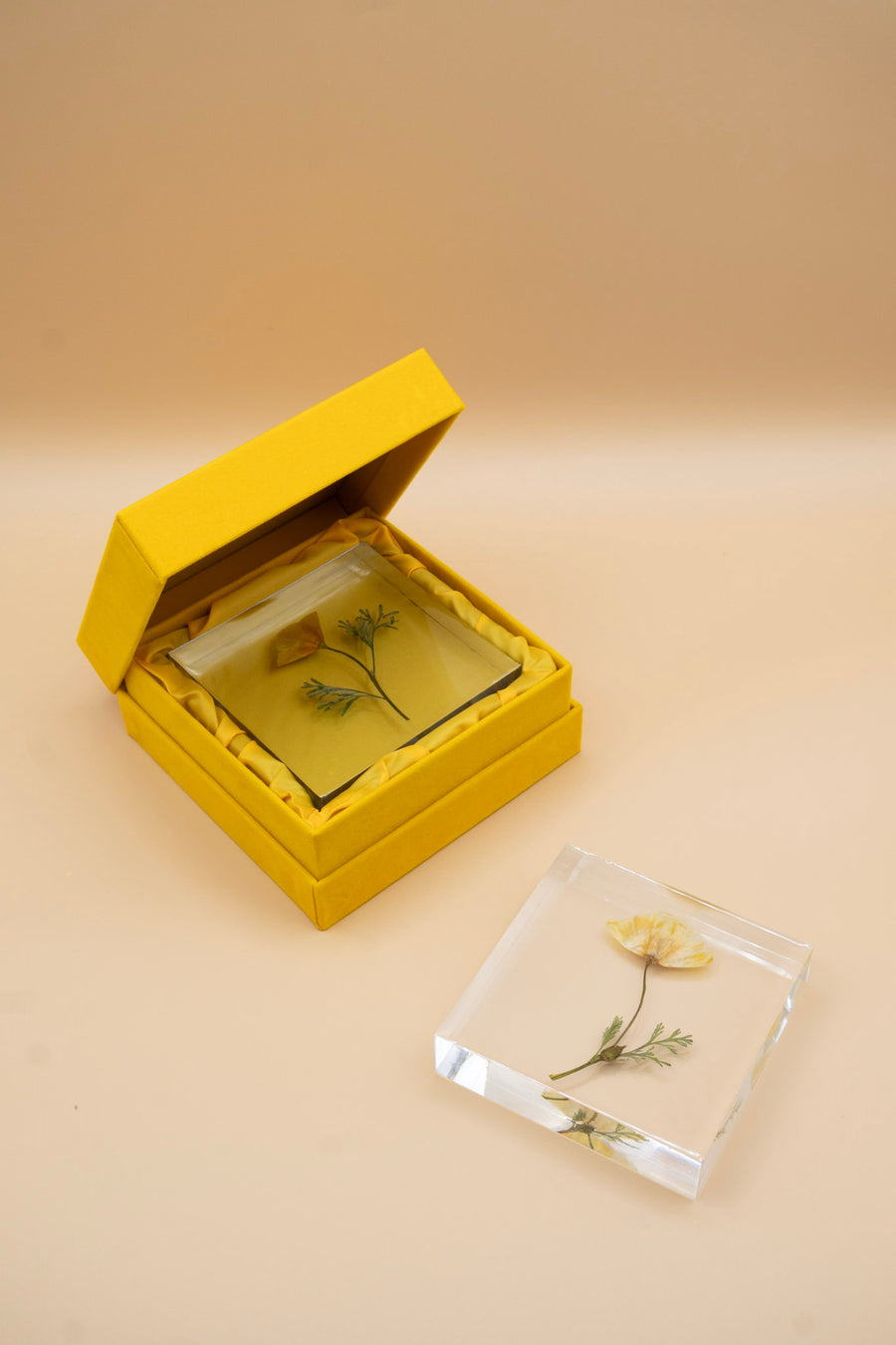 Yellow pressed flower resin jewelry box with a clear lid on a beige background