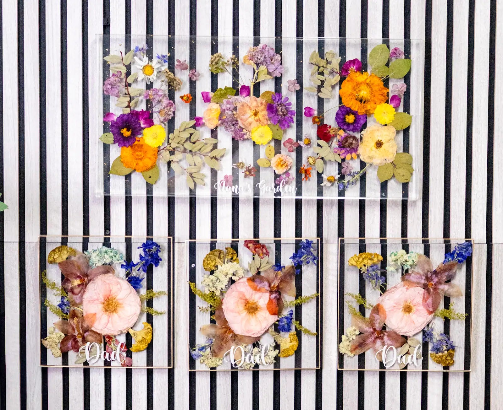Set of three decorative panels with pressed flowers on a black and white striped background
