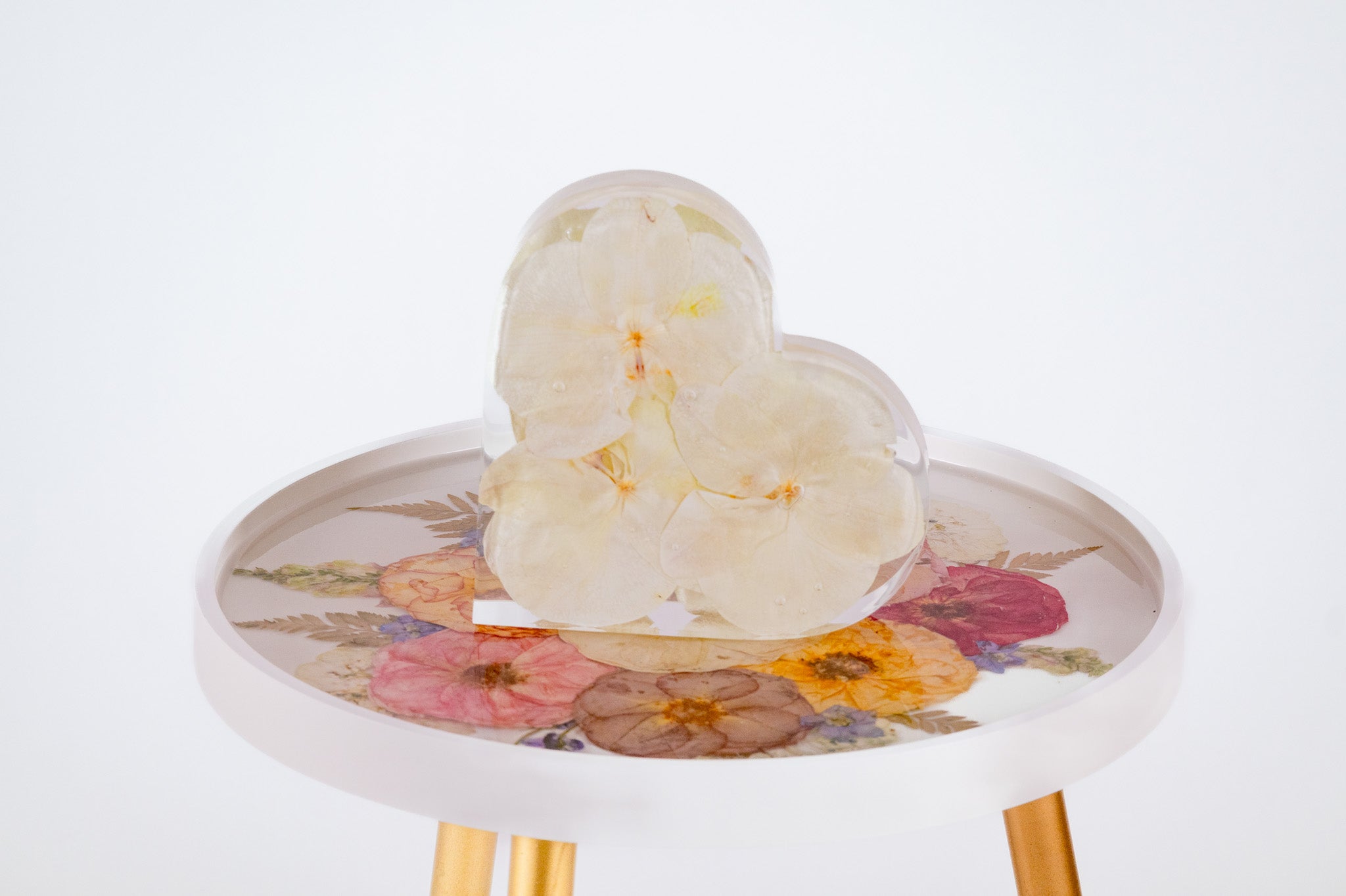 White orchid bouquet preservation inside of resin heart mold on a white table with preserved resin flowers on top.