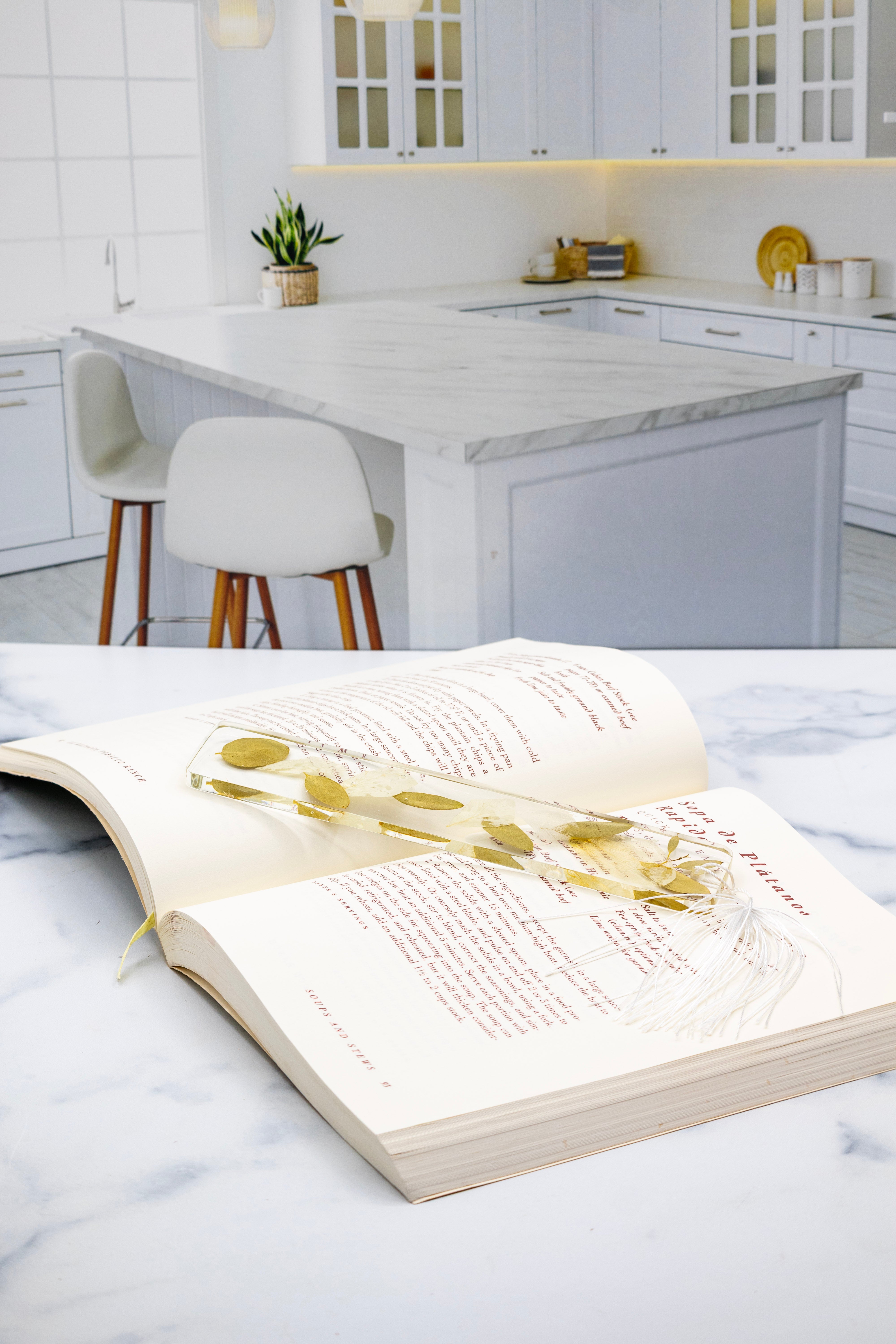 Open book with dried flower bookmark on a marble surface in a kitchen