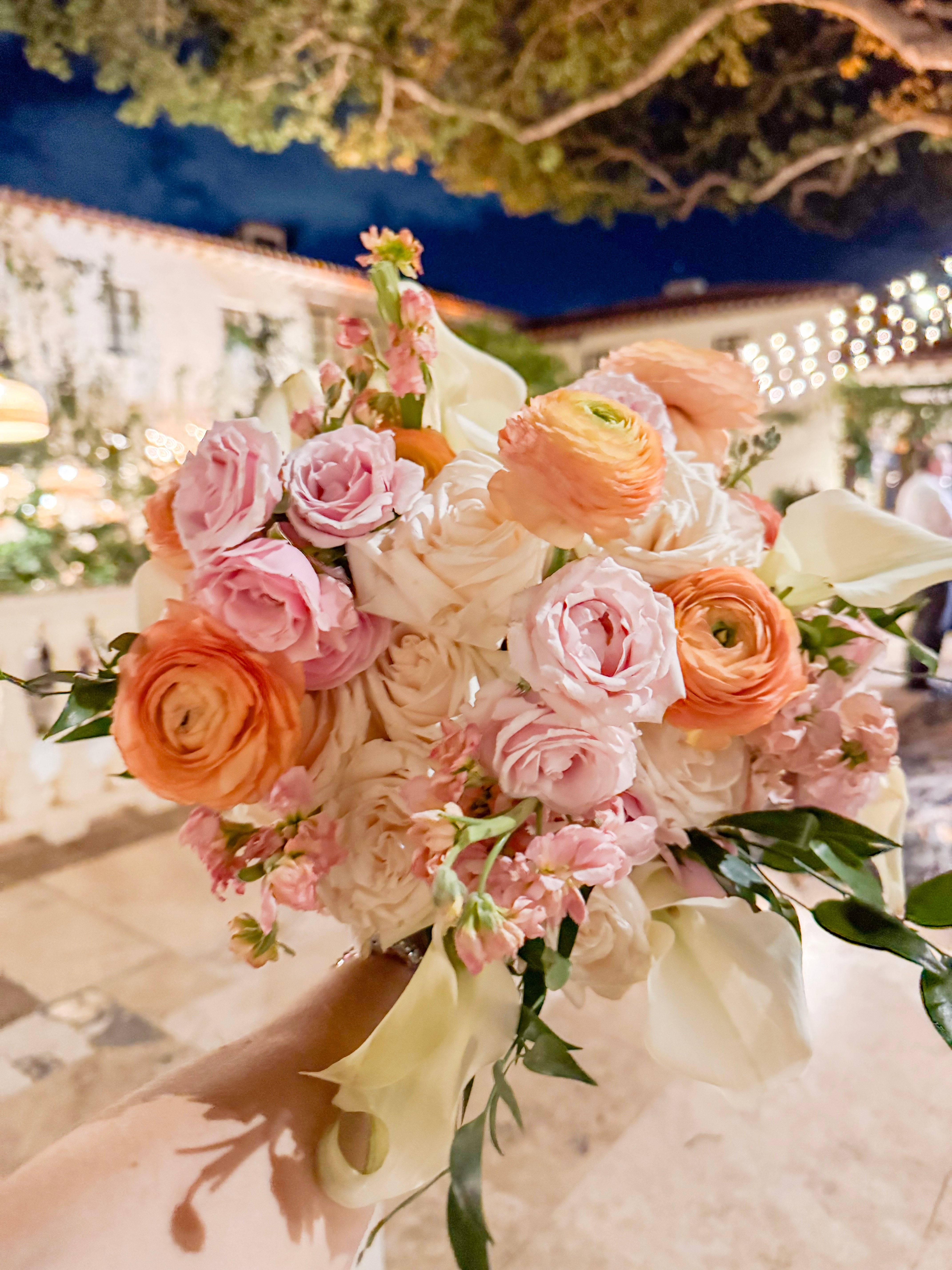 Bouquet of pink, orange, and white flowers held by a person outdoors at the Addison Boca Raton Bouquet Preservation Pickup Service