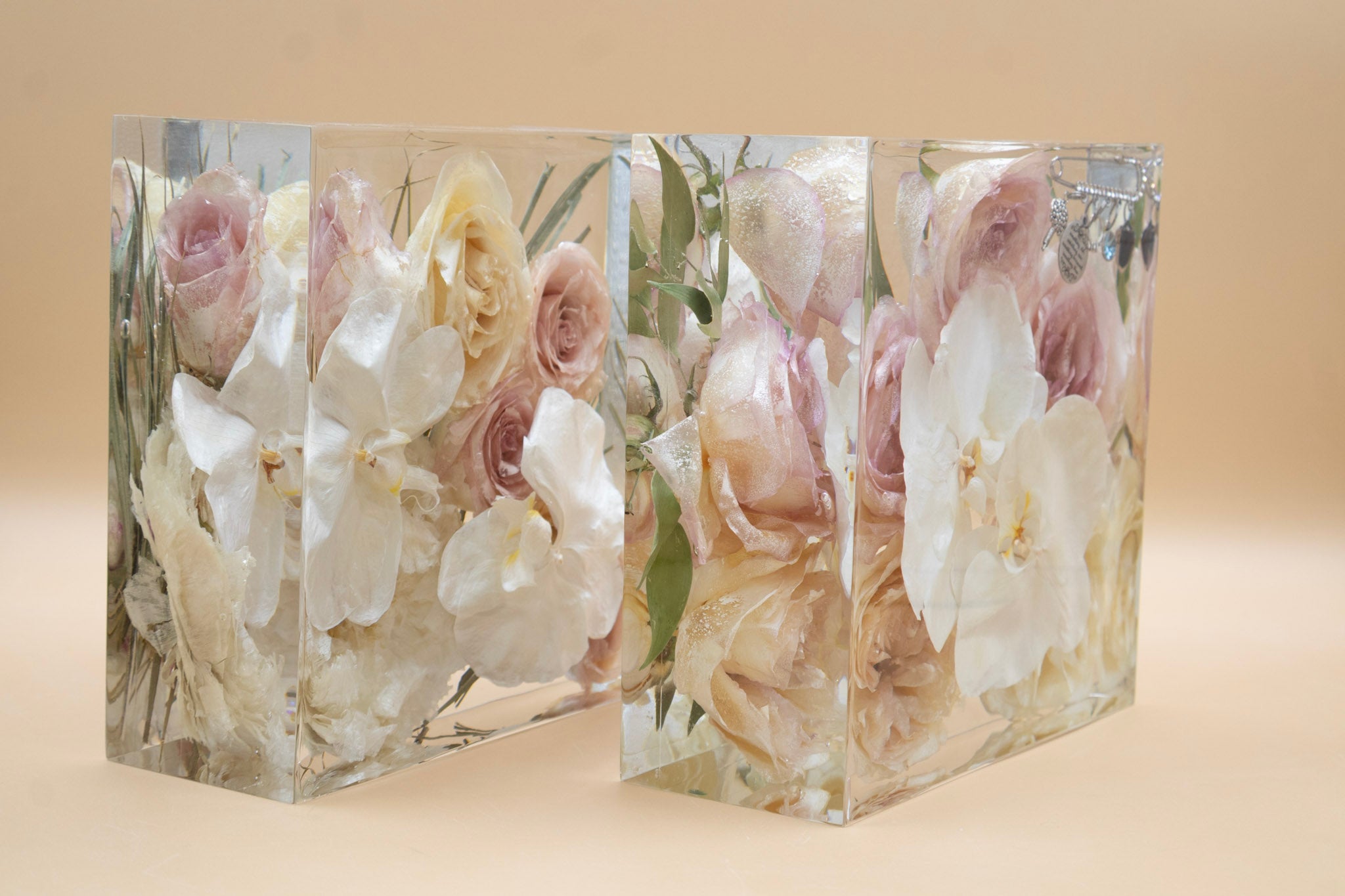 Side view of two clear resin blocks of preserved flowers and white orchids dried and arranged artistically