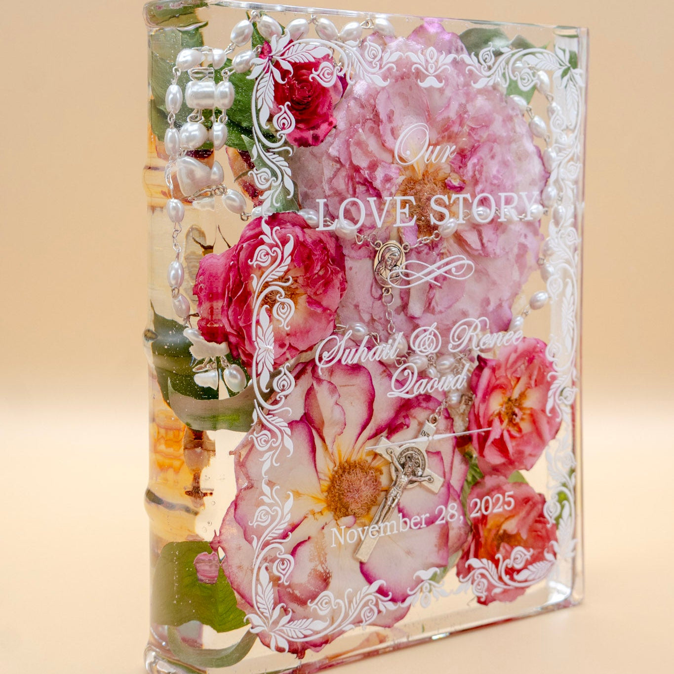 Book-shaped resin keepsake preserving pink wedding roses and a pearl rosary, personalized with a couple's names and date.