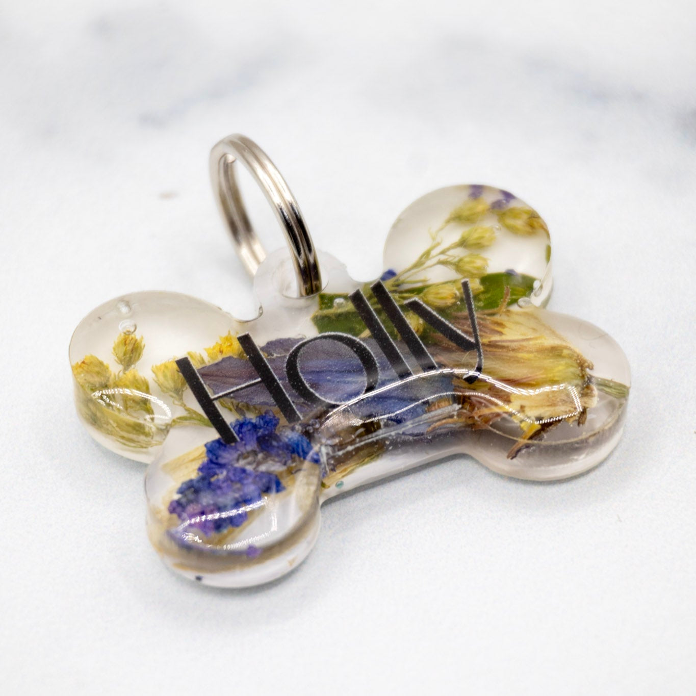 Landscape photo of a pressed flower resin bookend set with soft dried botanical layers on a white surface