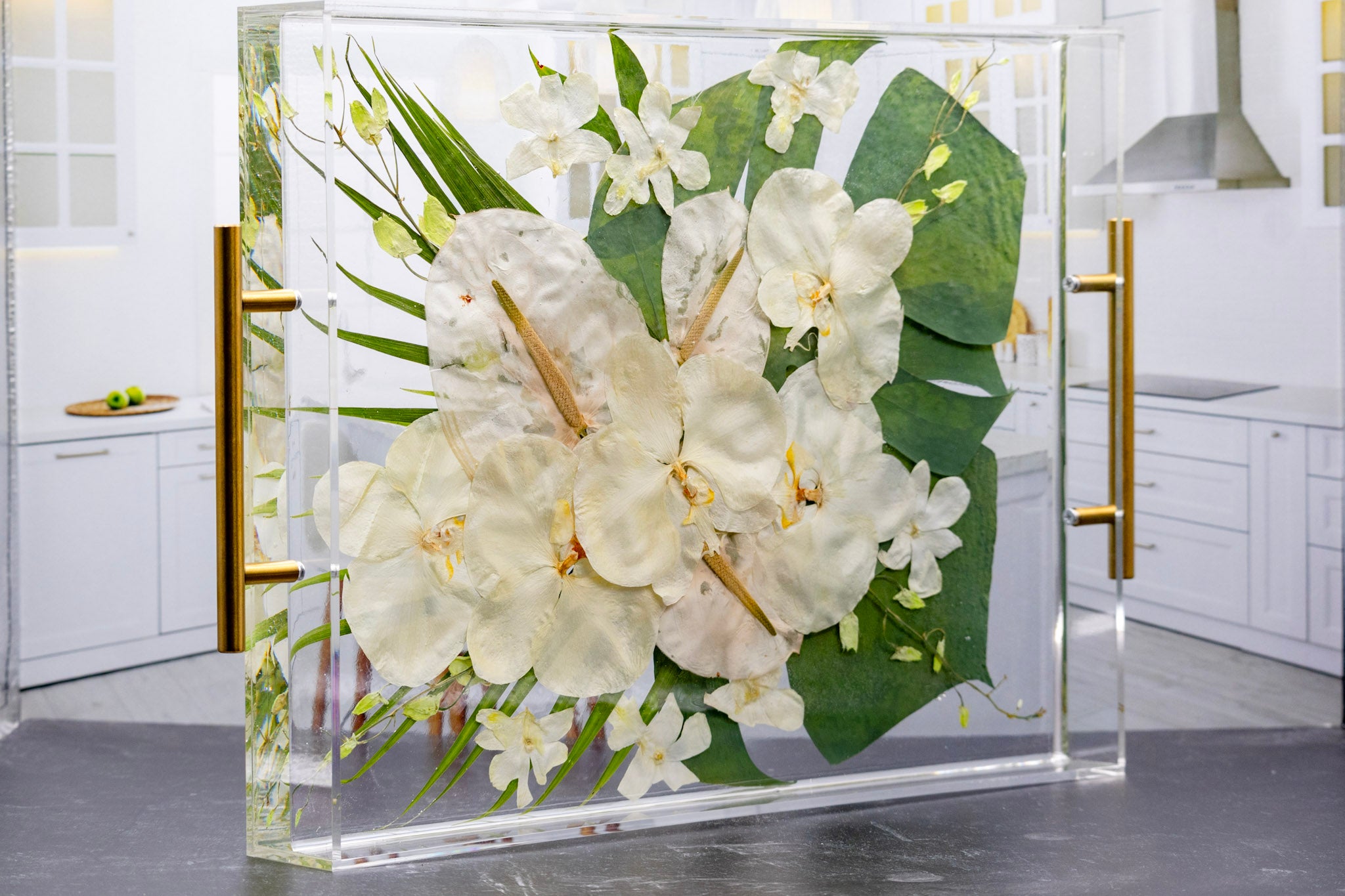 Preserved white tropical bouquet preservation in pressed flower serving tray with raised edges and gold handles on a black background