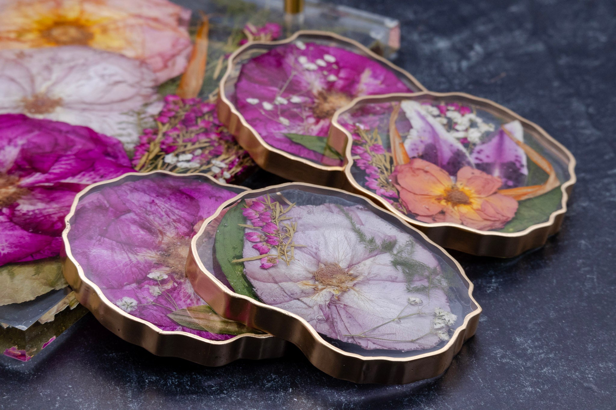 Set of 4 floral preservation coasters with gold edges on a dark surface