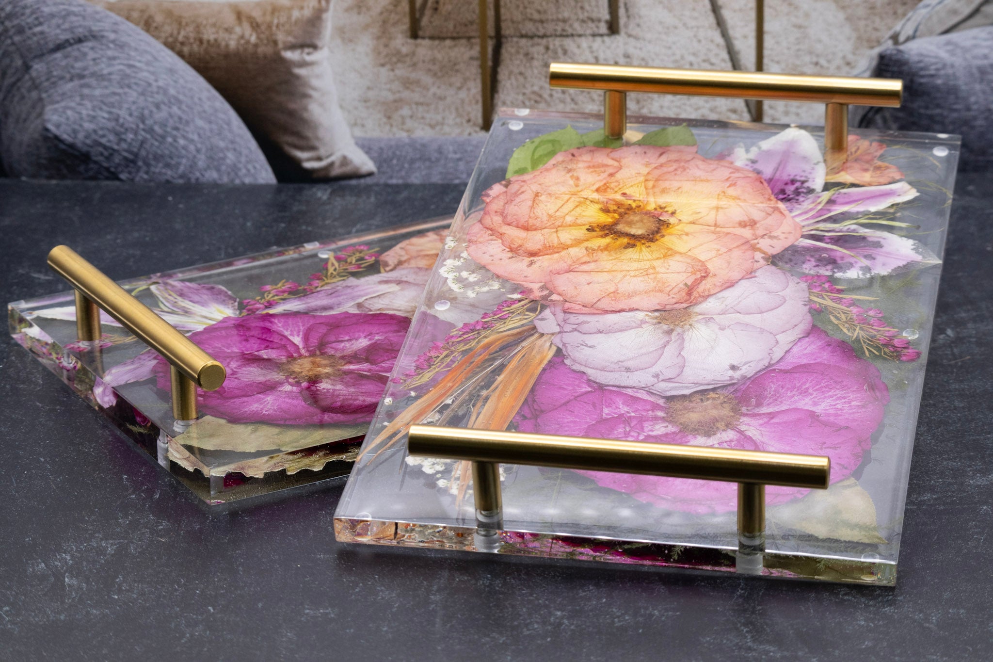 Clear acrylic tray with floral design and gold handles on a dark surface