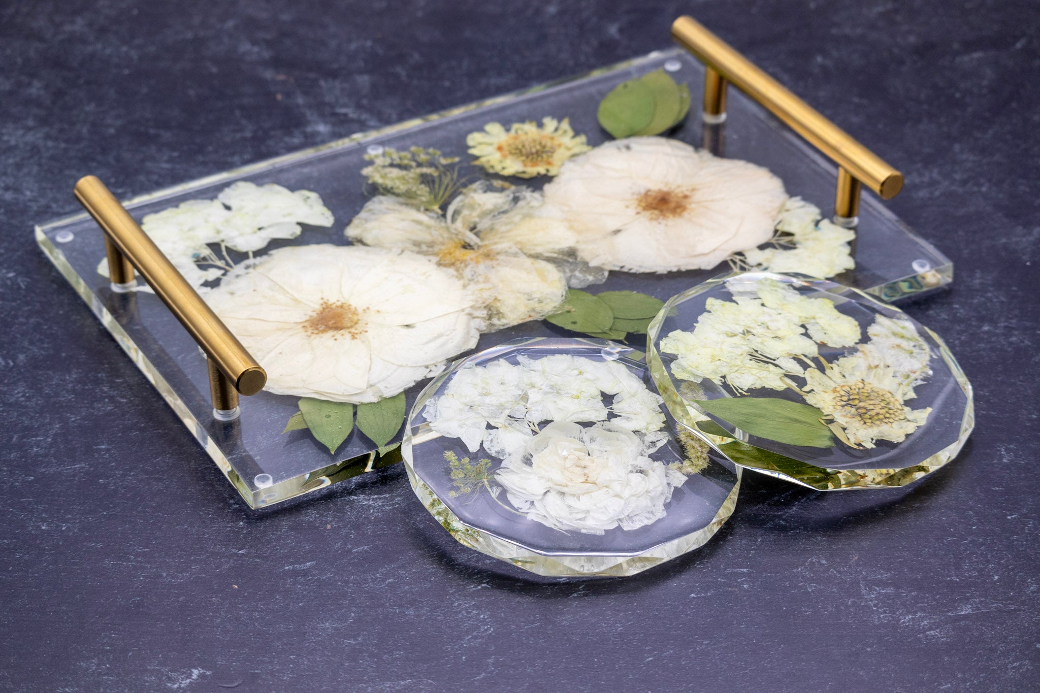 Decorative epoxy resin tray with real pressed flower coasters on a dark surface
