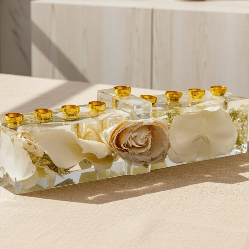 Jewish wedding flower preservation menorah with gold candle cups and color corrected white flowers on a gray surface.