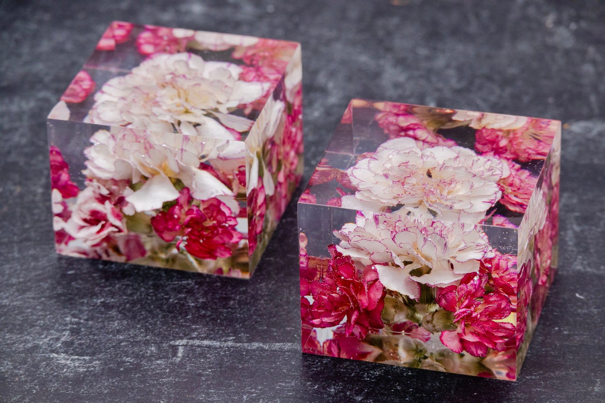 corsage preservation dried flower boutonniere Two square resin blocks with floral design on a dark surface