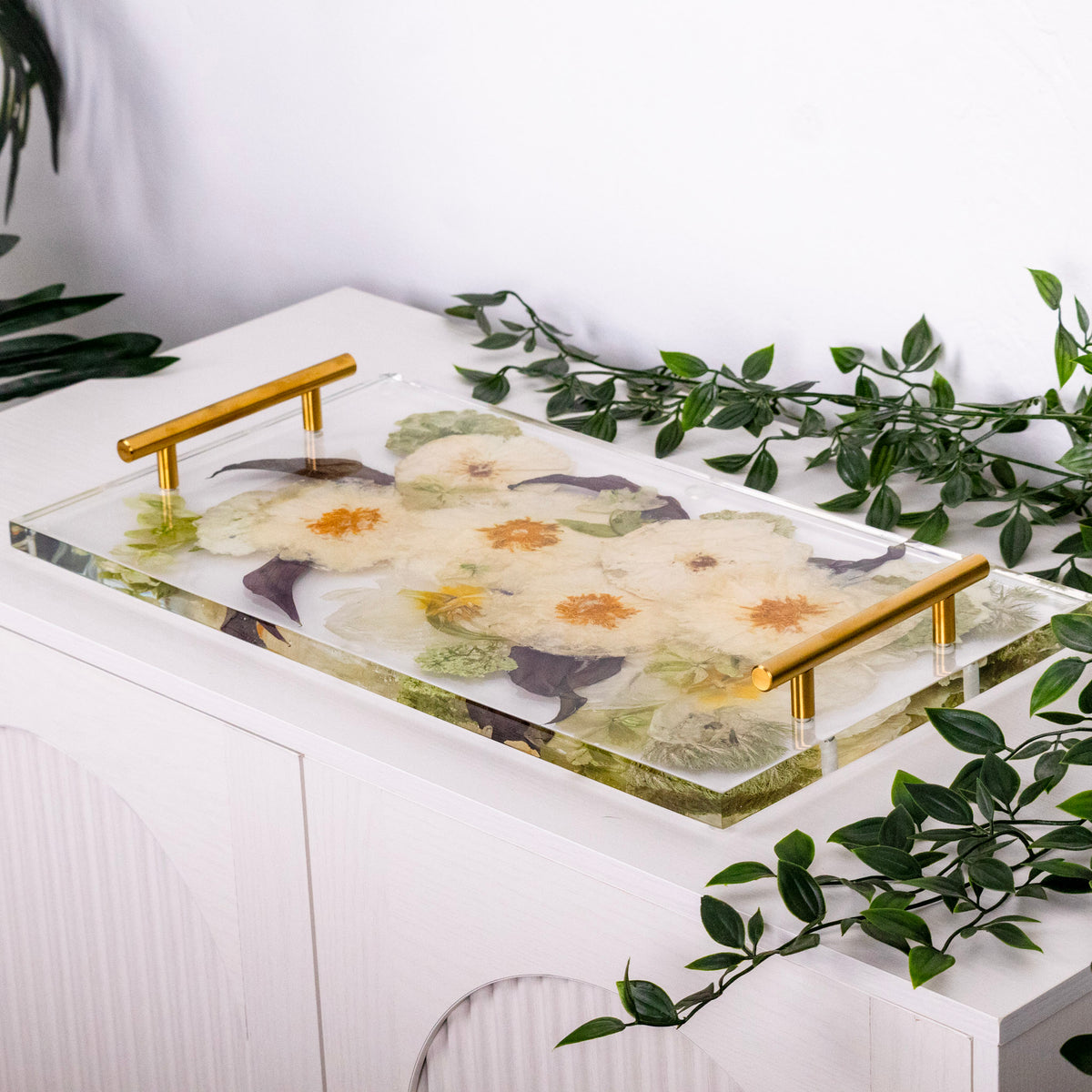 Clear acrylic serving tray filled with resin and preserved white flowers and greenery, finished with gold handles for a wedding keepsake.