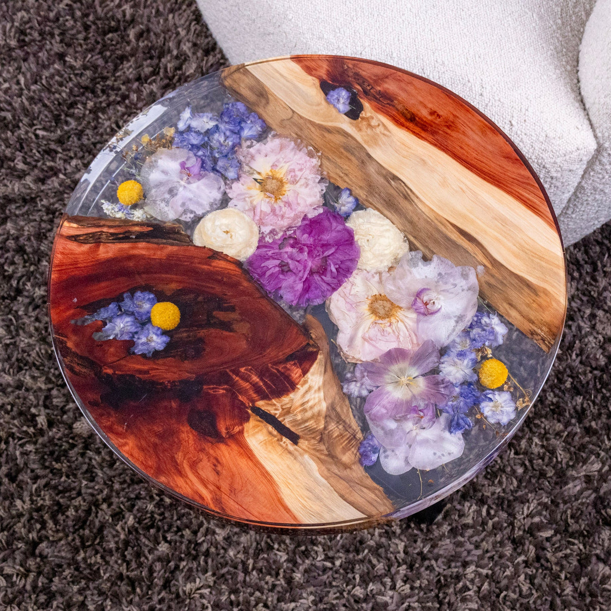 round resin wood table with purple and peony bouquet preserved between live edge wood