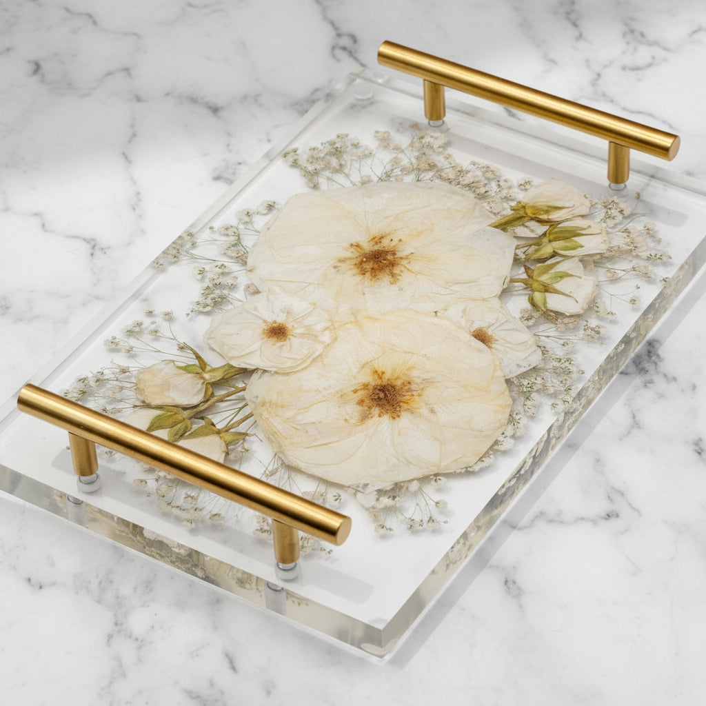 White Rose bouquet preservation rectangular clear resin art serving tray with two gold metal handles, featuring large pressed white roses in natural dried tone and small green leaves encased in epoxy flower preservation, set against a solid beige background.