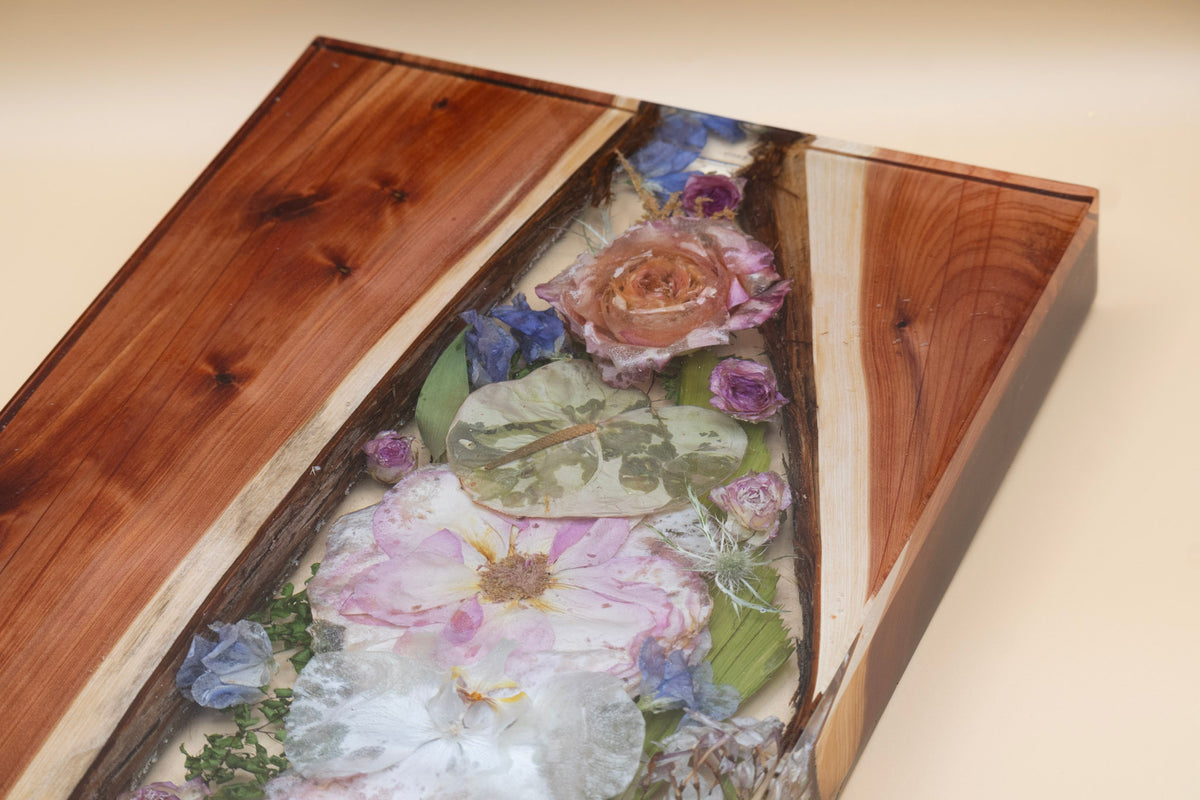 Close up of flower preservation roses, orchid and anthurium and live edge wood encased in resin