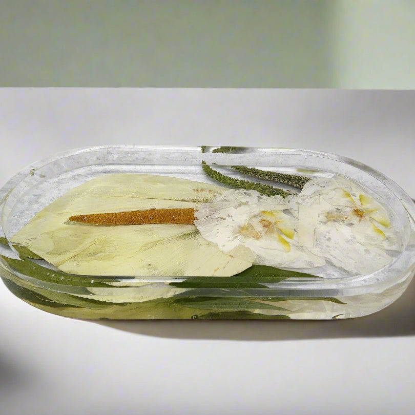 Oval pressed flower trinket tray with preserved calla lily on a bathroom counter