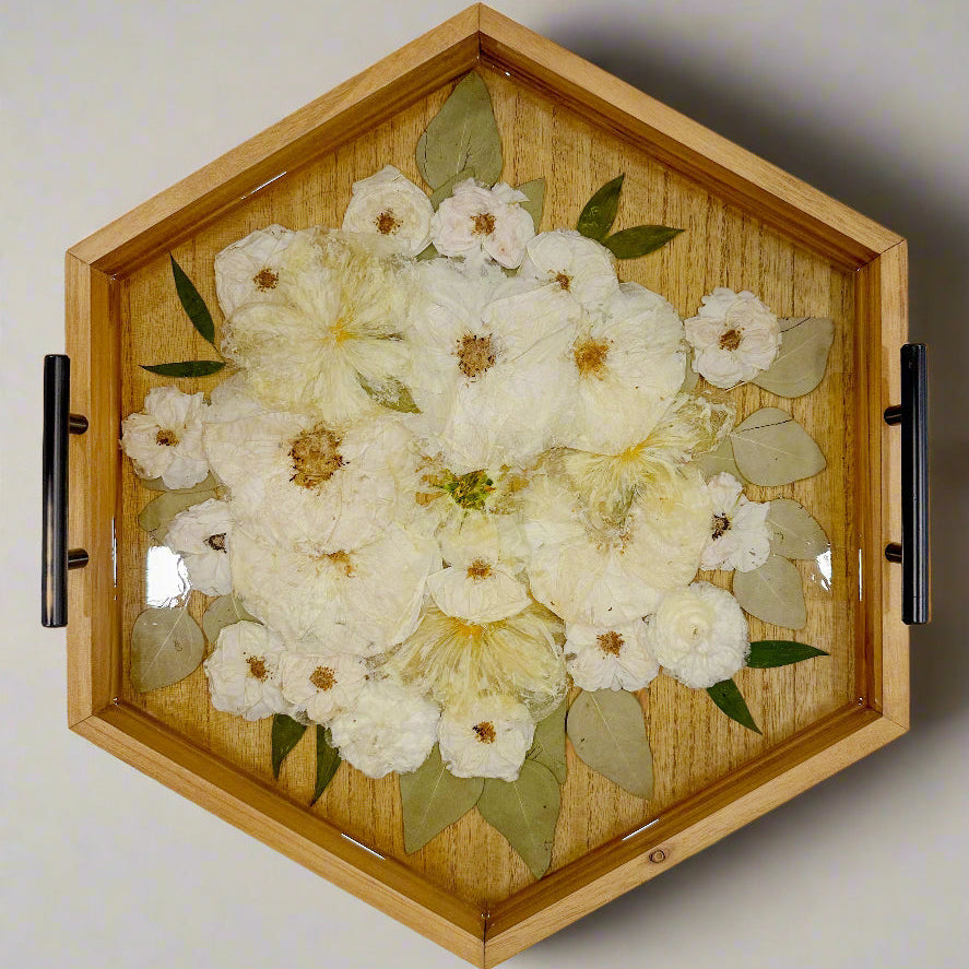 Natural wood tone ottoman tray featuring white rose and white peony in clear resin with black handles on a grey background
