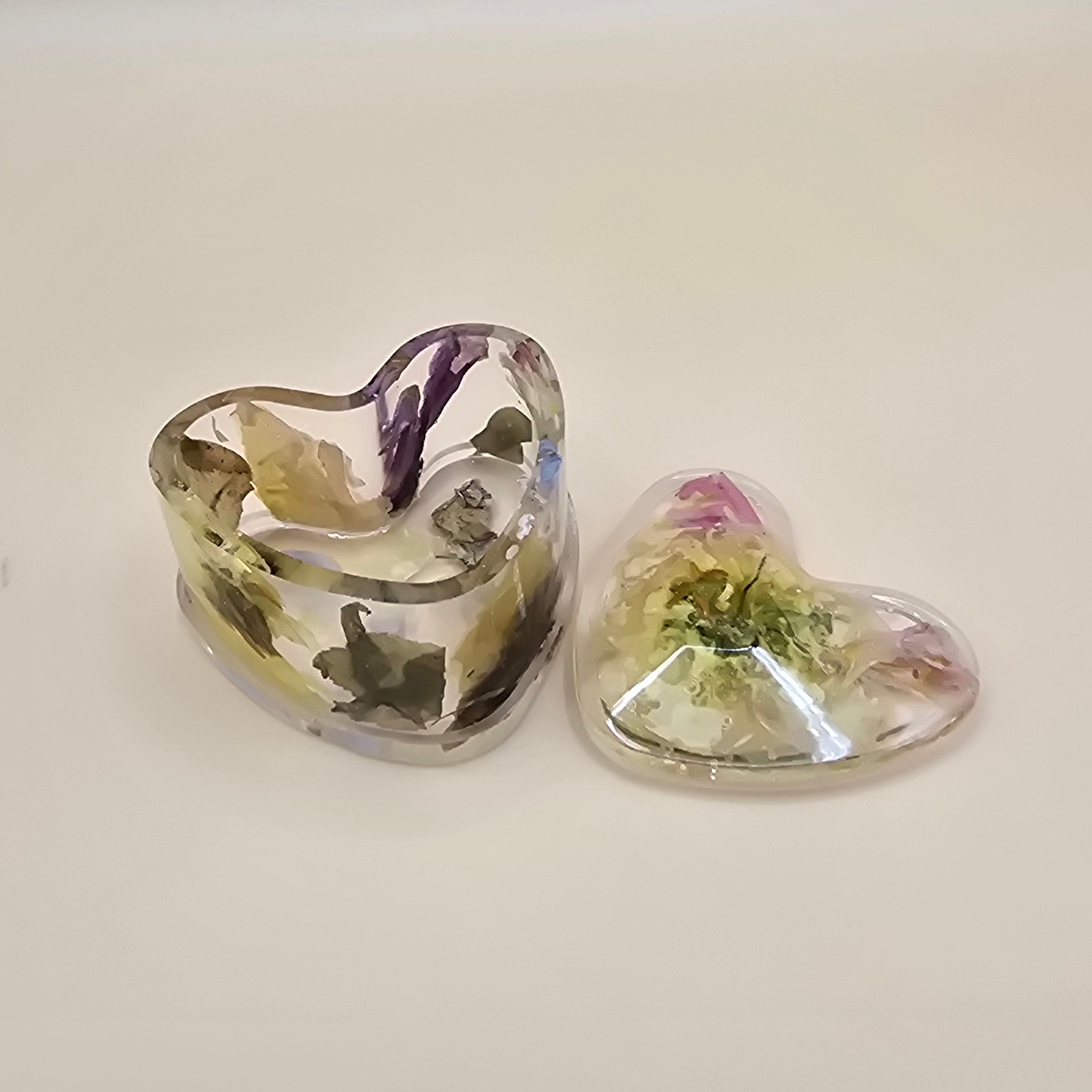 Two piece heart-shaped resin jewelry box with embedded flowers on a light background