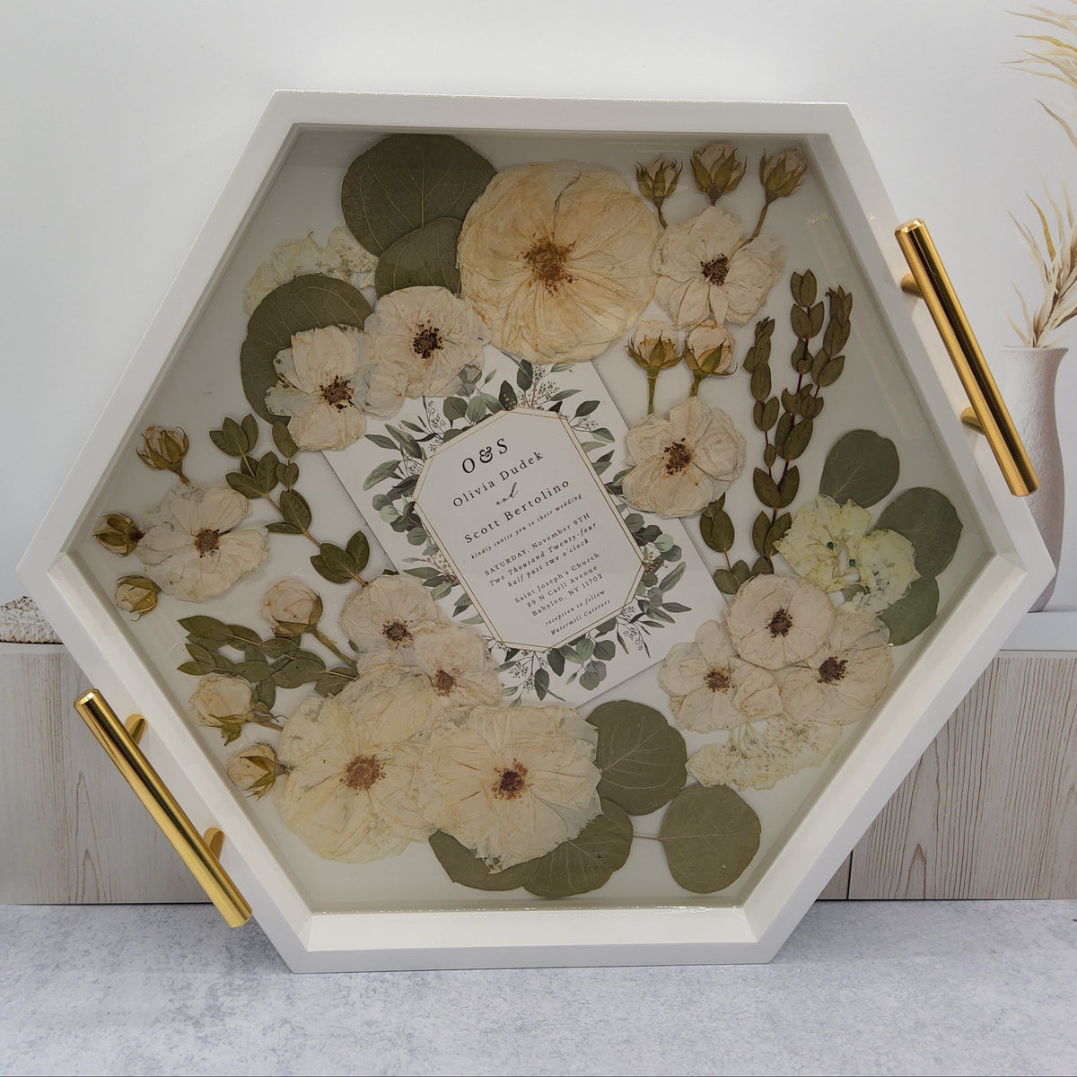 White wood serving tray with raised edges and gold handles pressed flower hexagon ottoman tray with dried white roses, eucalyptus and wedding invitation inlay