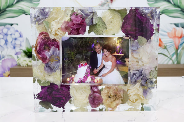 A preserved flower photo frame with a 5x7 photo opening, featuring a colorful floral design around the frame's border.