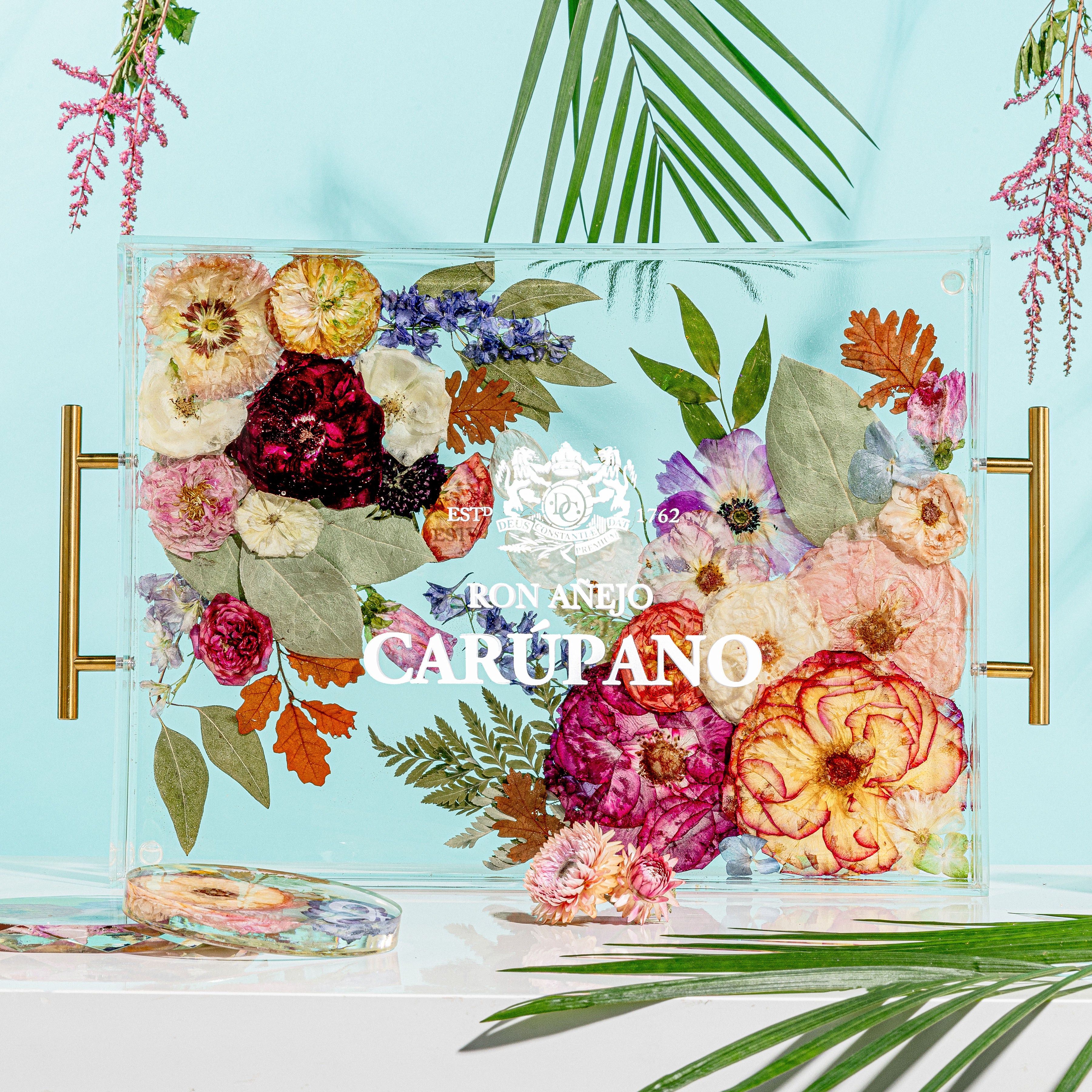 A large rectangle serving tray with a raised edge featuring pressed flowers and metallic flakes, with handles on the sides.
