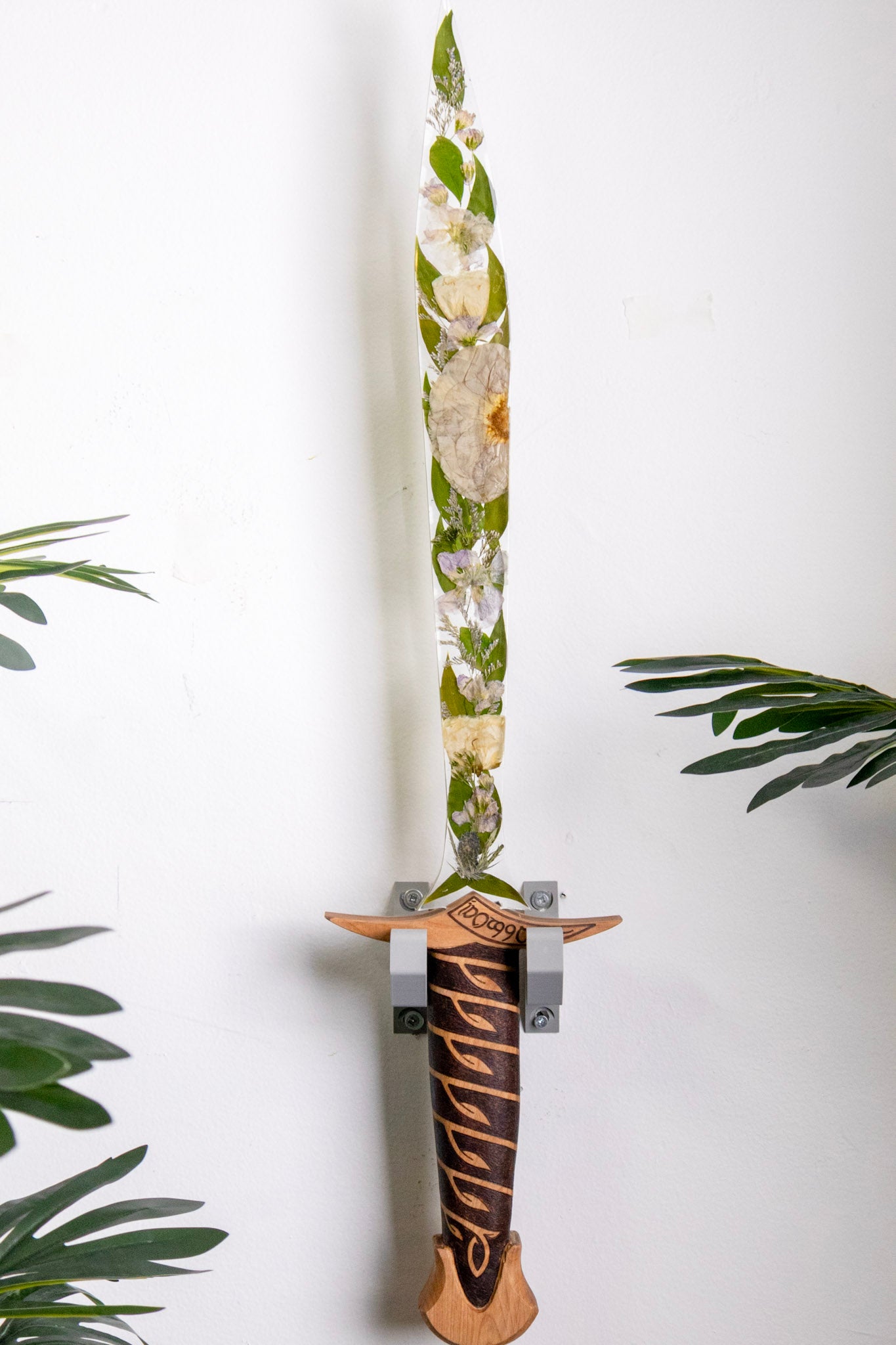 decorative resin sword with preserved wedding bouquet in the blade with wood handle hanging on the wall