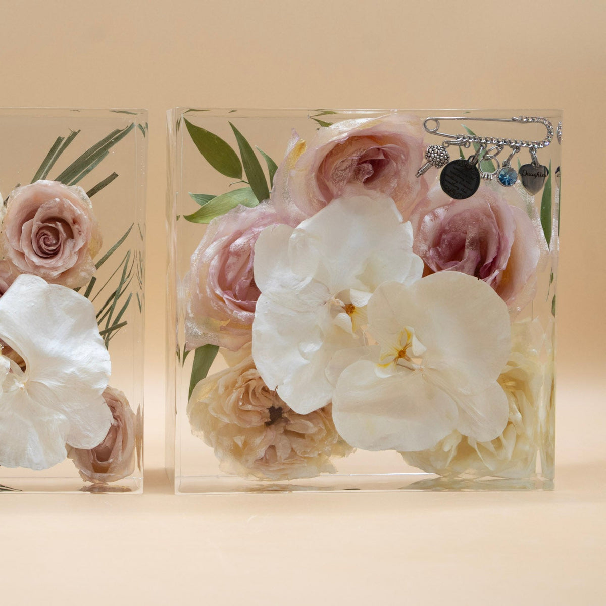 Two clear resin blocks of preserved flowers and white orchids dried and arranged artistically with memorial pin from wedding bouquet handle encased inside.