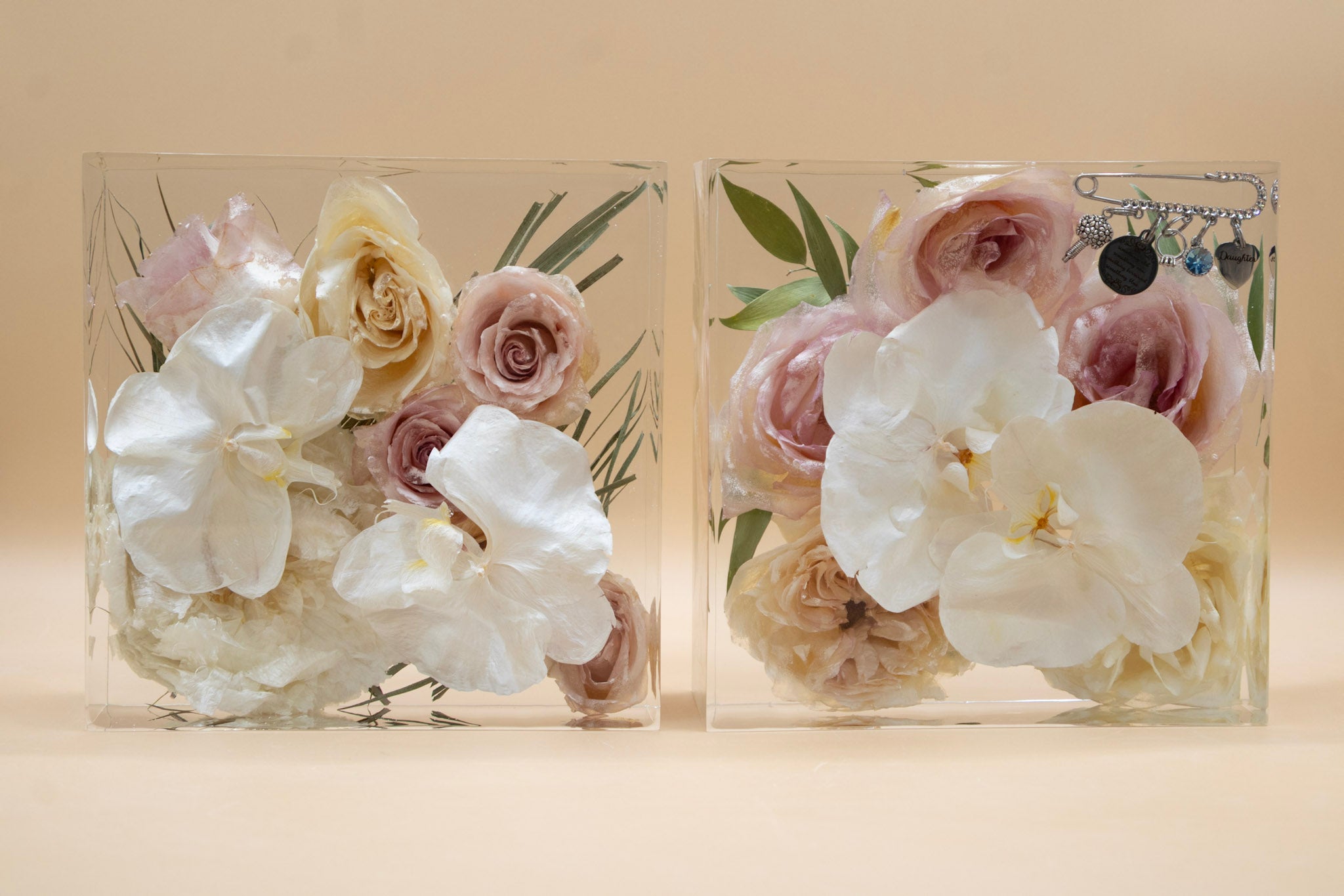 Two clear resin blocks of preserved flowers and white orchids dried and arranged artistically 