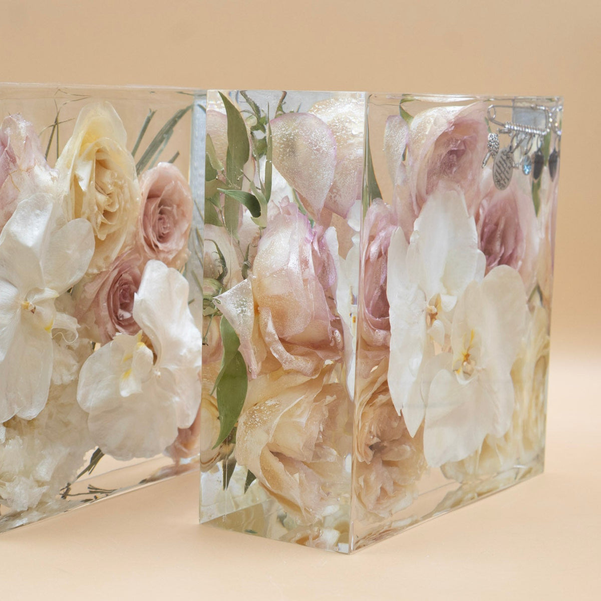 Side view of two clear resin blocks of preserved flowers and white orchids dried and arranged artistically 
