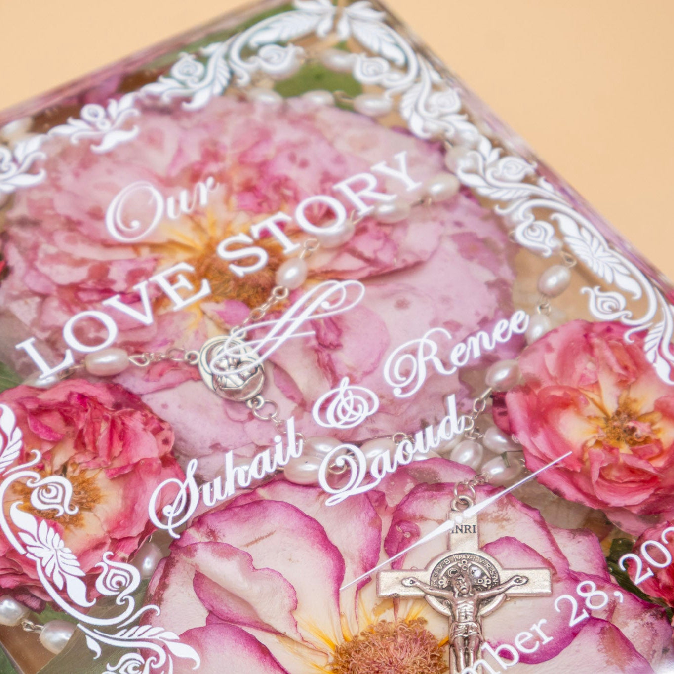 Book-shaped resin keepsake preserving pink wedding roses and a pearl rosary, personalized with a couple's names and date.