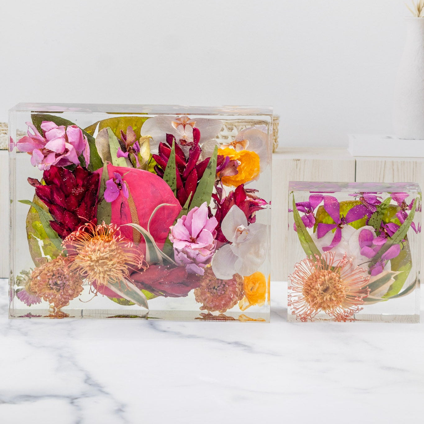 Two clear resin bouquet preservation dried flower bookends on a marble surface.