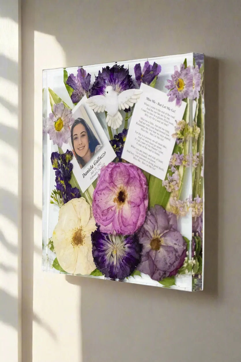 Decorative wall art with pressed flowers and a photo of a woman on a gray wall.