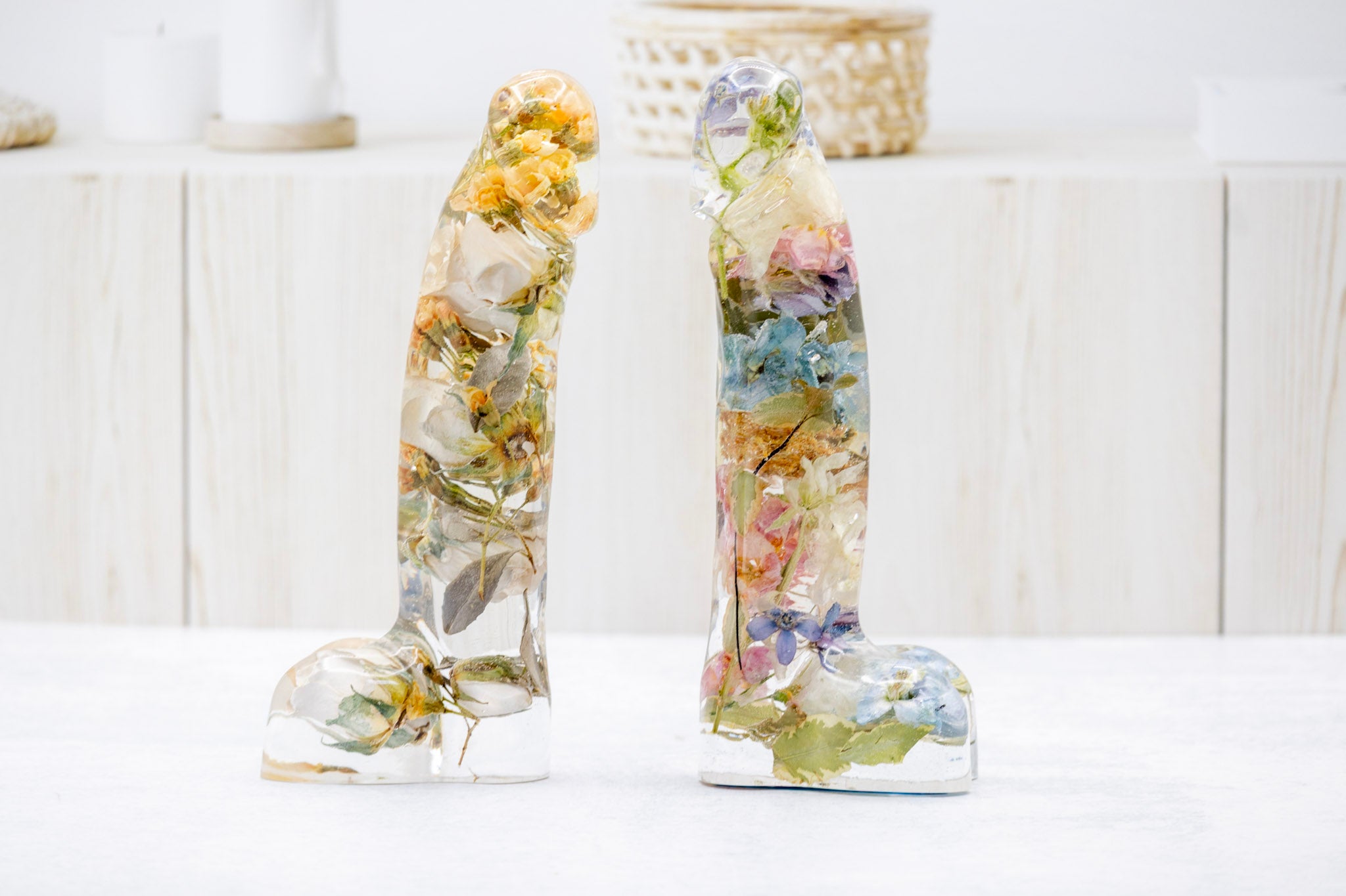 Two decorative resin penis shape dildo with real preserved flowers on a white background