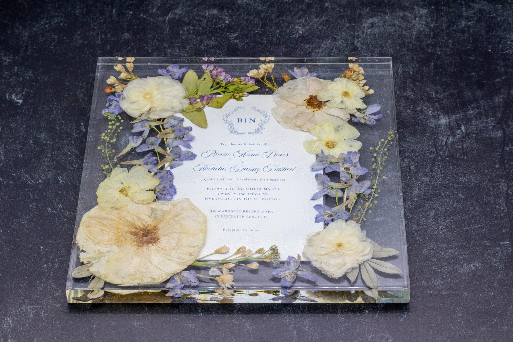 Pressed roses and pressed blue delphinium flowers in resin floating frame with preserved wedding invitation