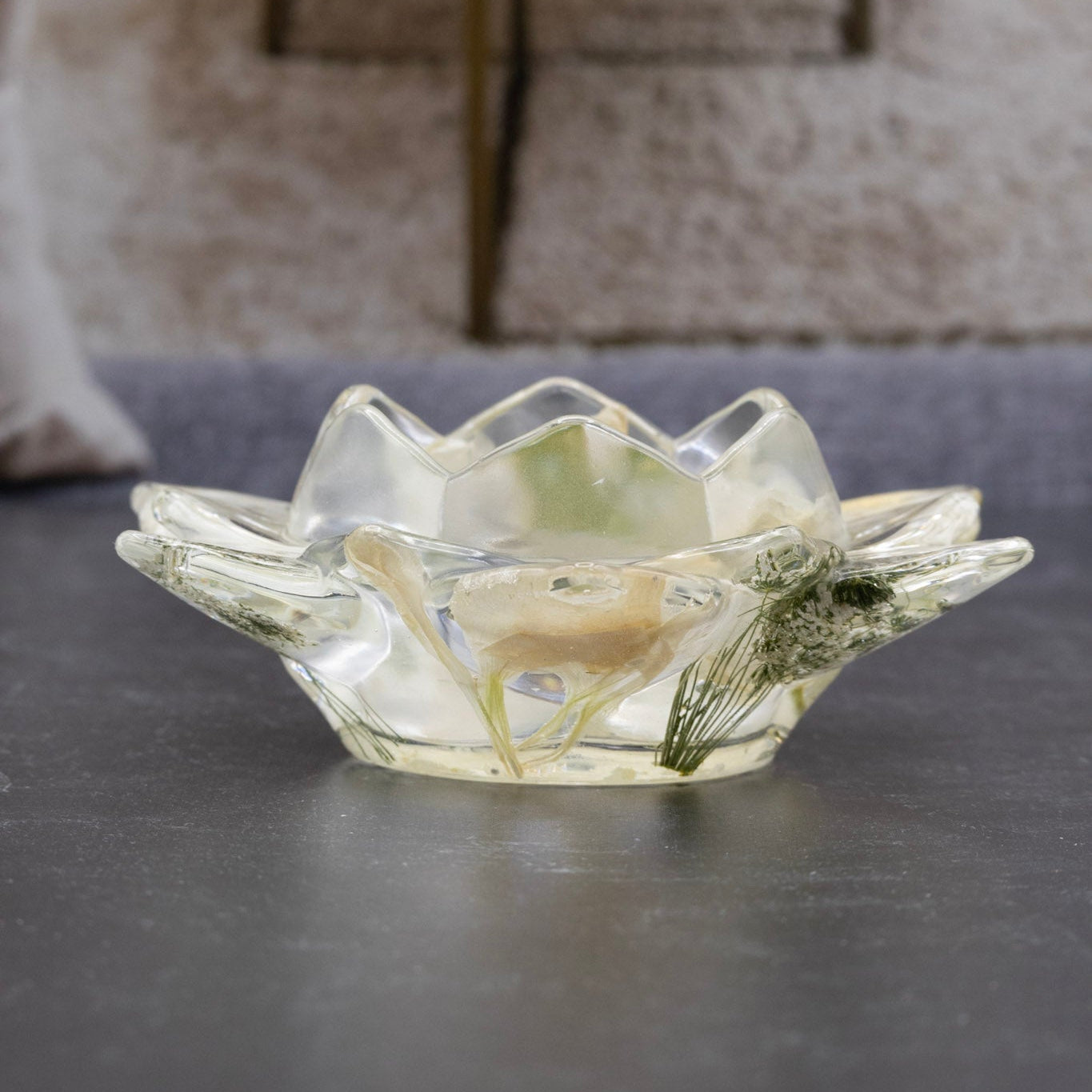Decorative glass bowl with a candle on a dark surface