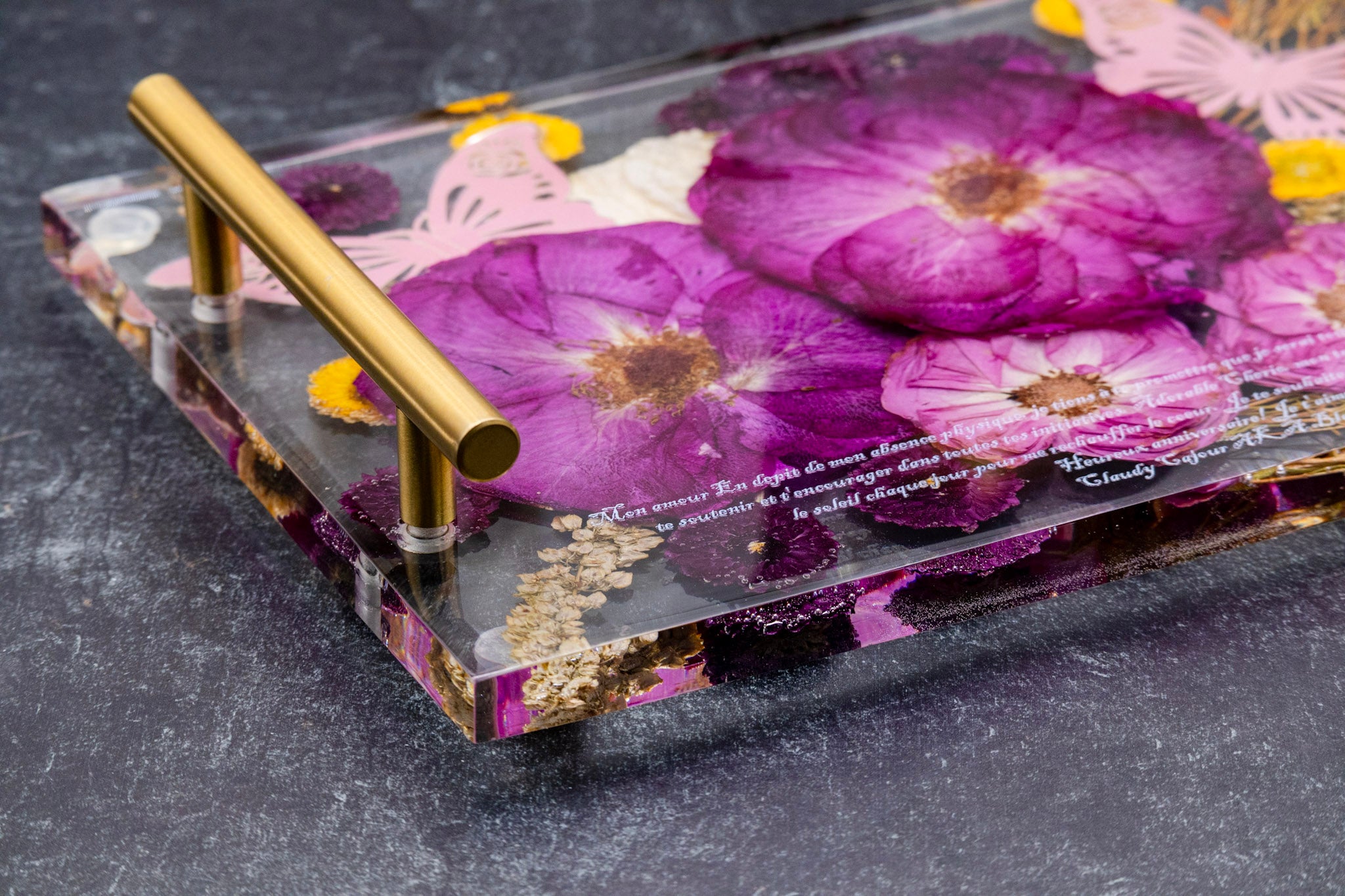 Decorative tray with floral design and gold handle on a dark surface