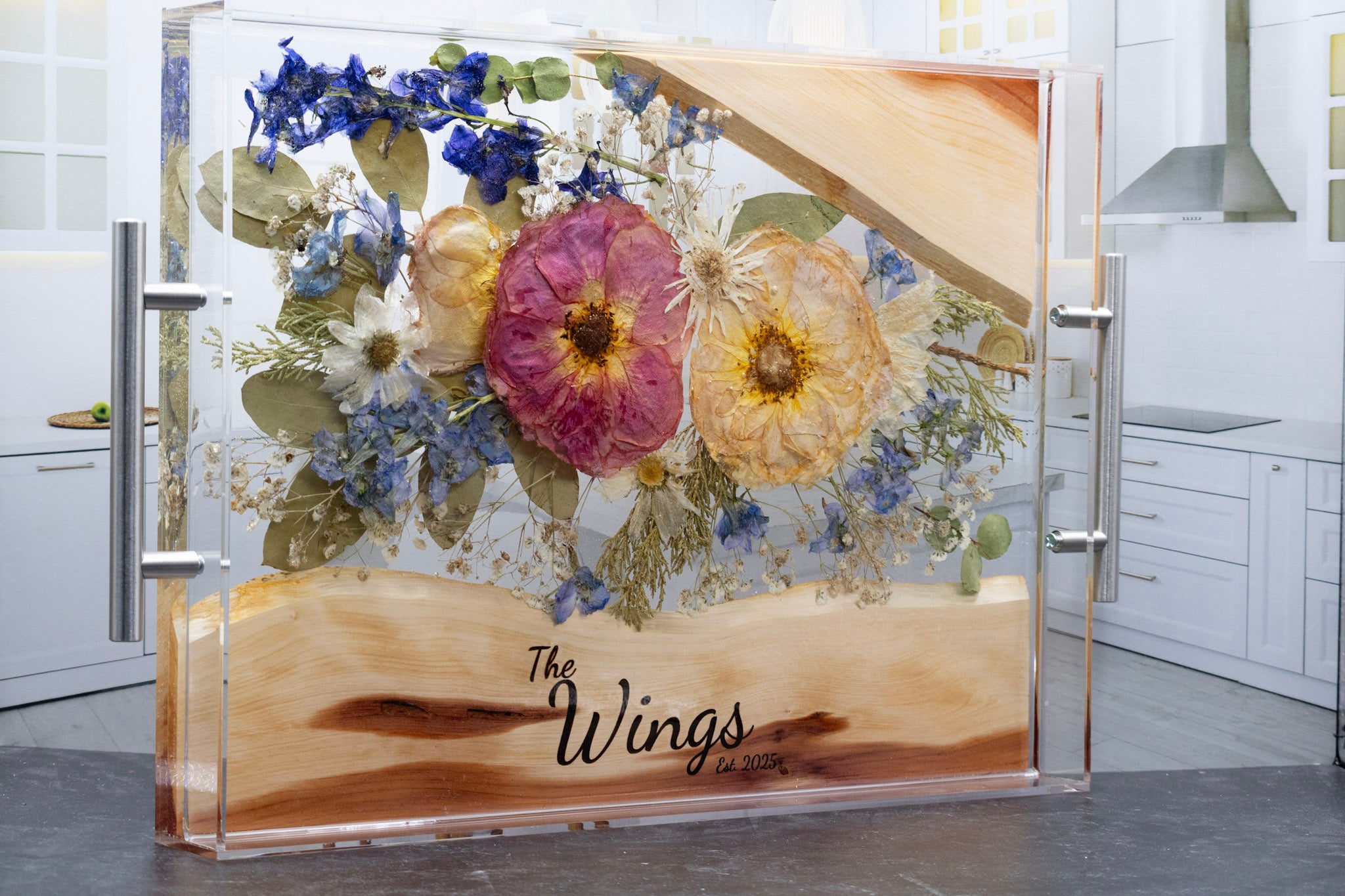 Decorative resin tray with floral design and 'The Wings' branding in a kitchen setting.
