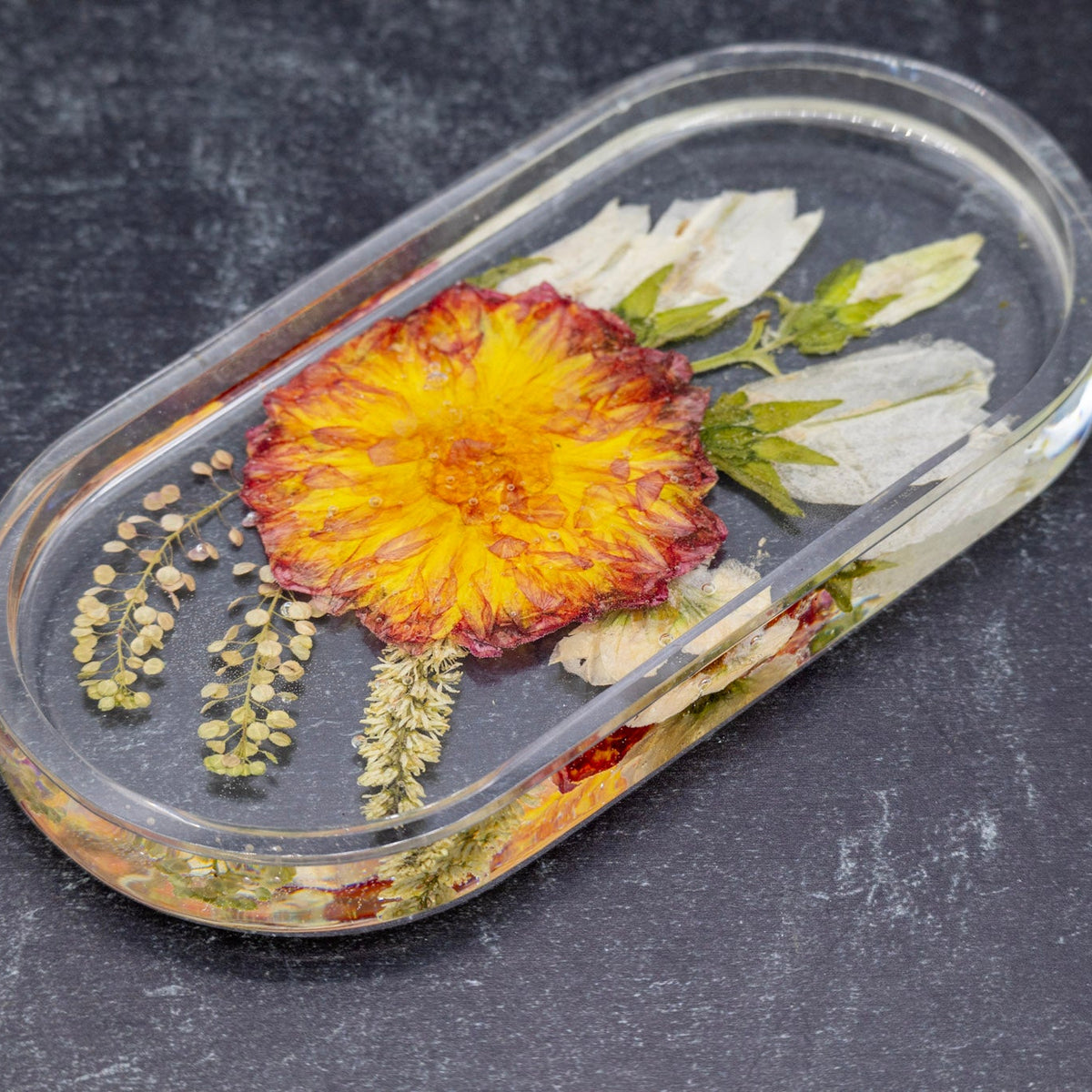 Pressed orange Dahlia flower preservation dried dahlia preservation oval tray on a dark background 