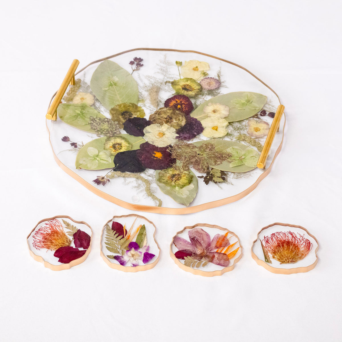 Round resin tray with gold handles and four geode coasters, preserving pressed flowers and leaves in a wedding keepsake set.