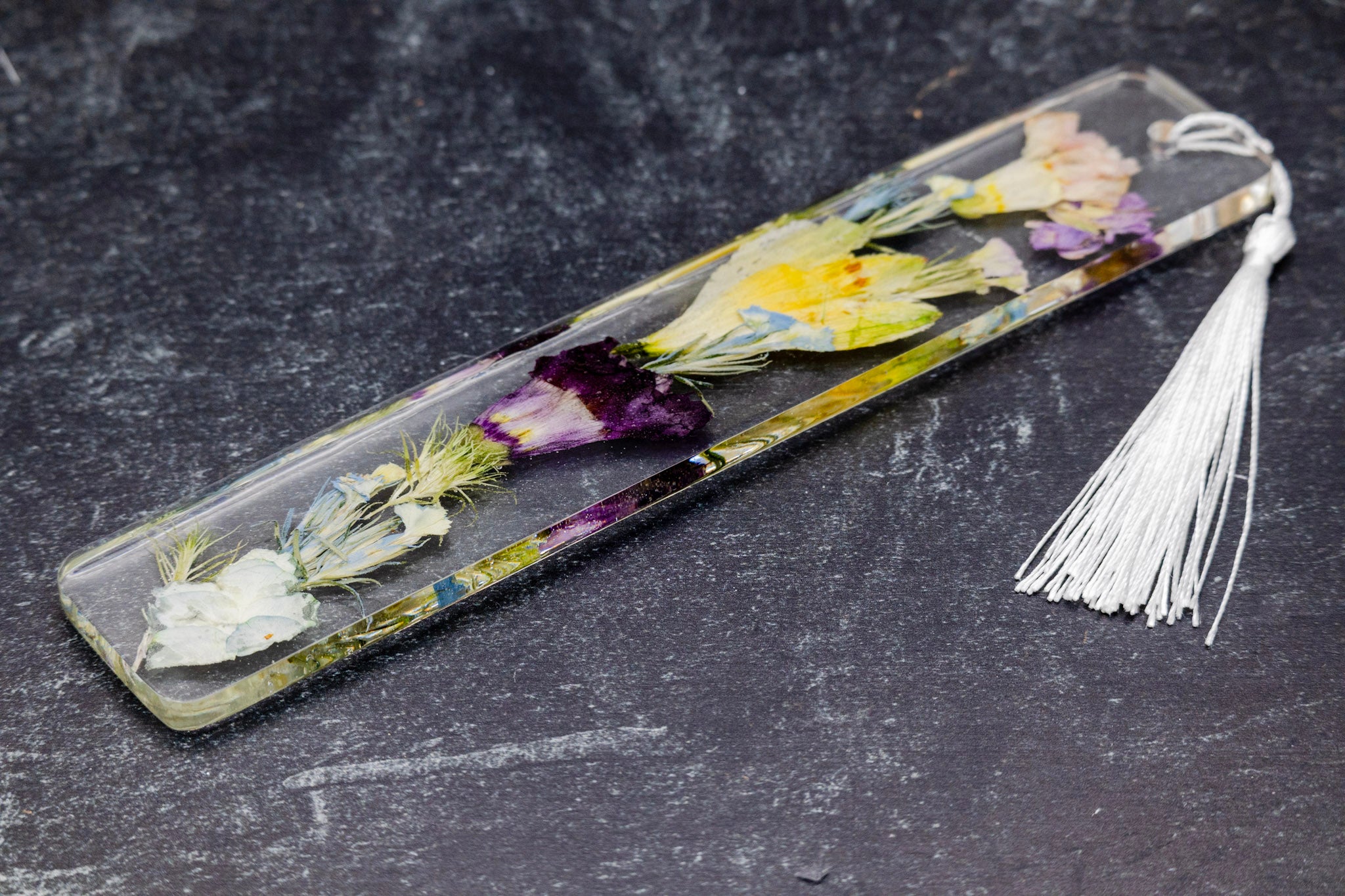 Bookmark with pressed flowers on a dark surface