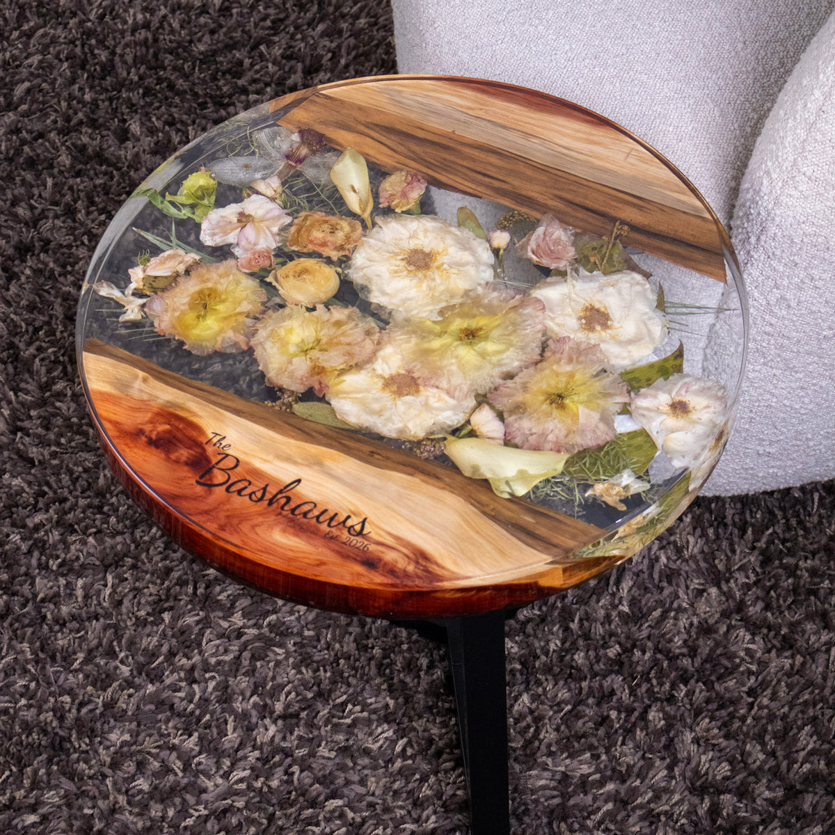wood resin flower preservation round side table with laser engraved personalized text, black legs on dark brown shag rug