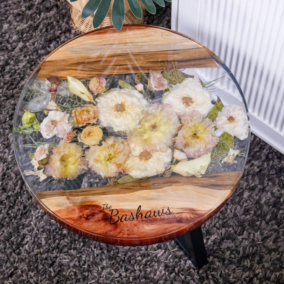 Wedding bouquet preservation in table made of live edge wood and epoxy resin featuring laser engraved text personalization of the last name and date, "The Bashaws Est. 2026"
